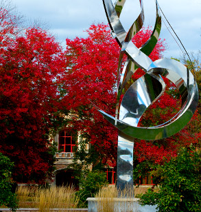 Flame of the Millennium sculpture on 山Ƶ campus with fall foliage and Moench Hall in background.